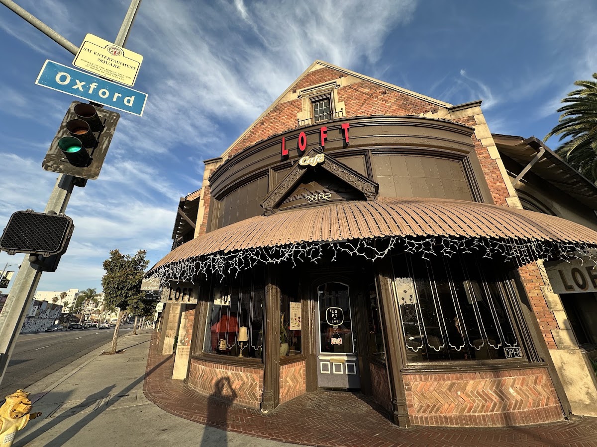 The brick corner building housing Cafe Loft, with its red LOFT neon sign and scalloped awning
